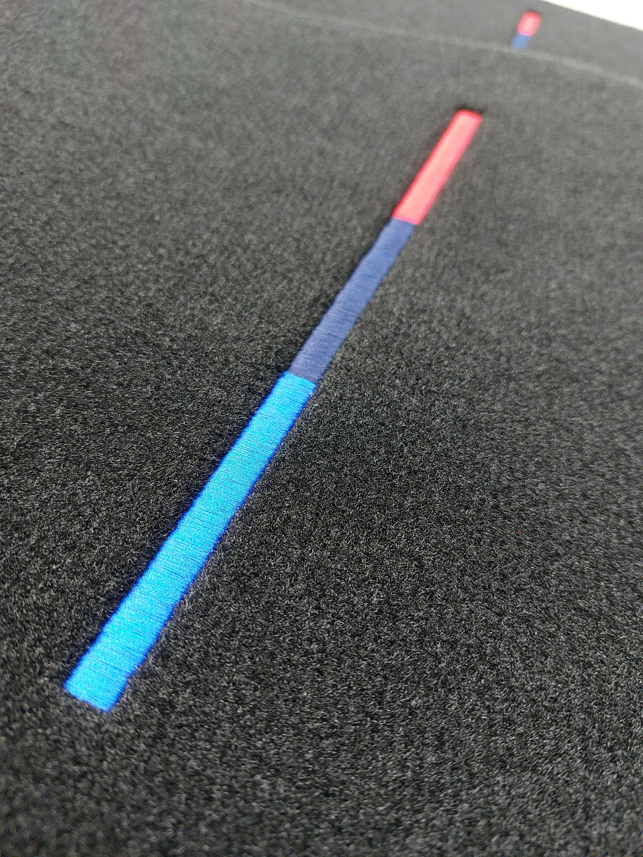 Eine Detail Aufnahme des Stick Logos in M-Farben.